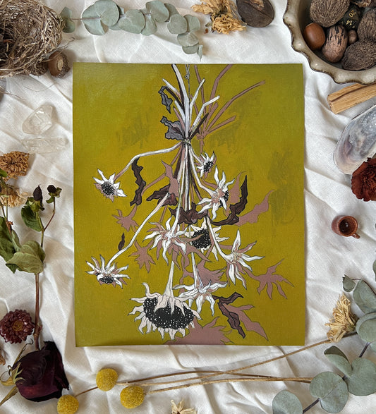 Art print of dried sunflowers with green background. Print is on a white linen cloth with natural dried flowers and other nature items surrounding it.