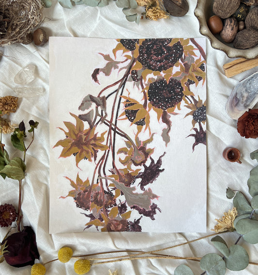 Art print of dried sunflowers with off white background. Print is on a white linen cloth with natural dried flowers and other nature items surrounding it.