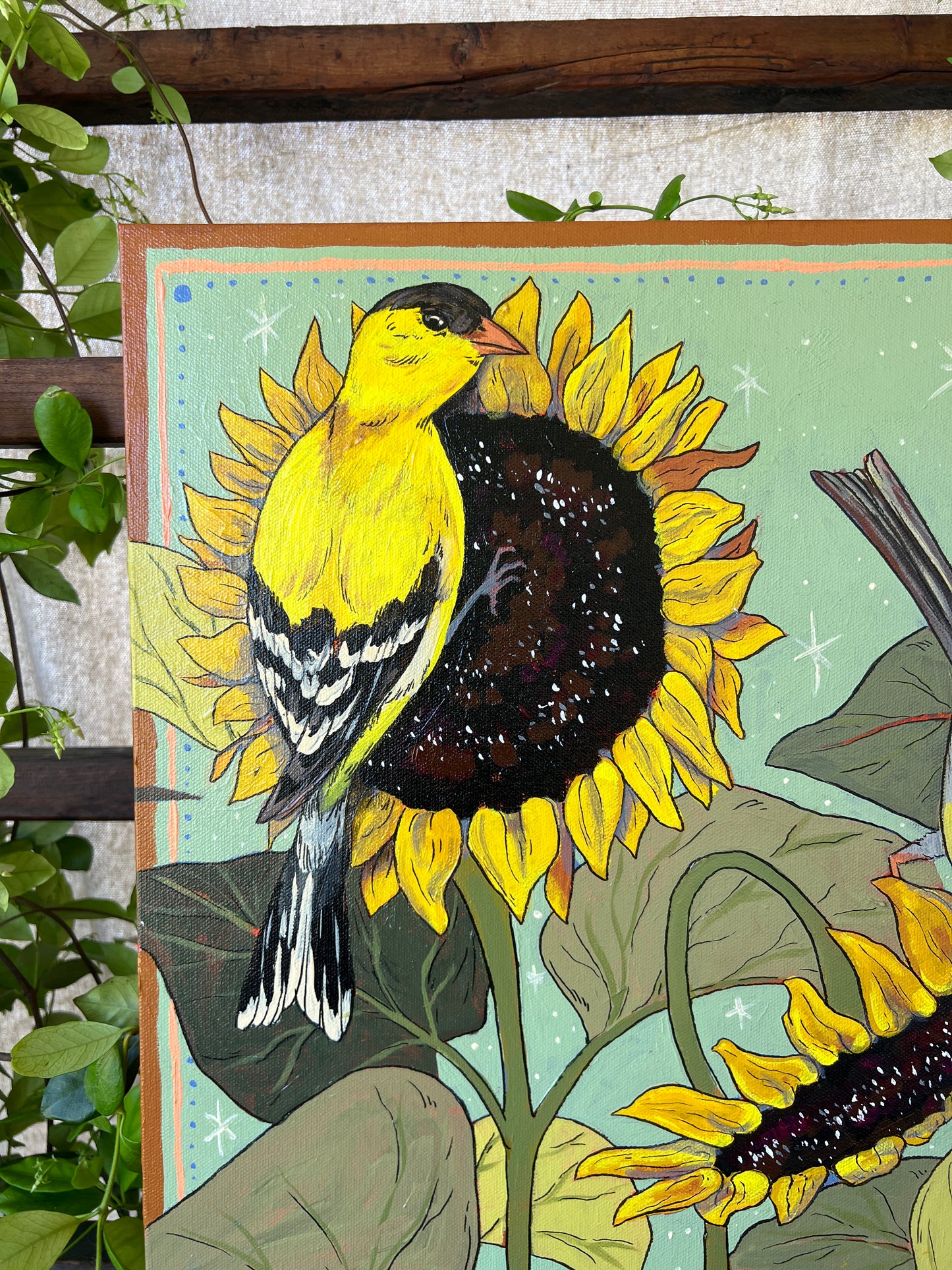 Detail of original painting with male gold finch on sunflowers, surrounded by greenery