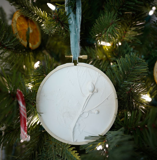 plaster cast of a dogwood branch in a round wooden embroidery hoop frame with a light blue velvet ribbon
